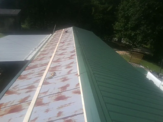 Old rusted panels beside newly installed green metal roofing — Wind Damage Roof Repair by Roofing Brothers in Twain Harte