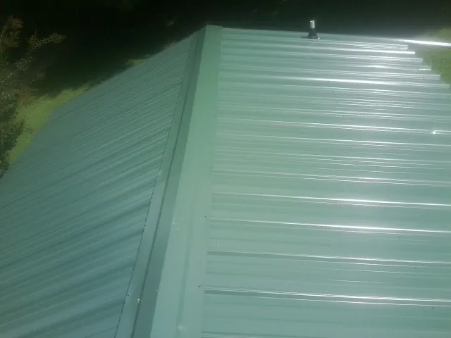 New green metal panels meeting at the ridge of a roof — Flat Roof Repair work by our crew in Twain Harte