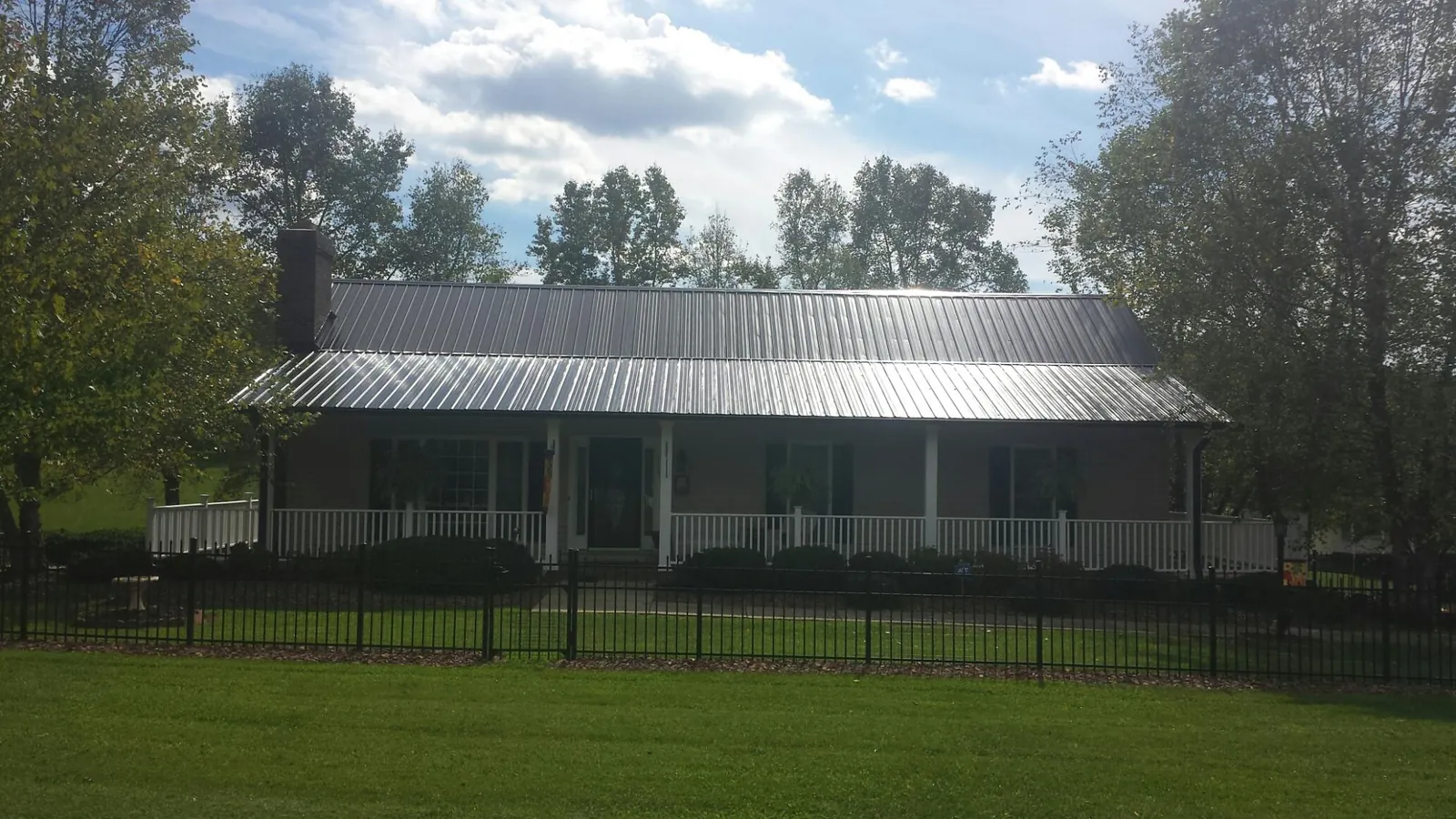 Gray metal roof on a brick ranch with a full width front porch — Gutter Guard Installation work by our crew in Twain Harte