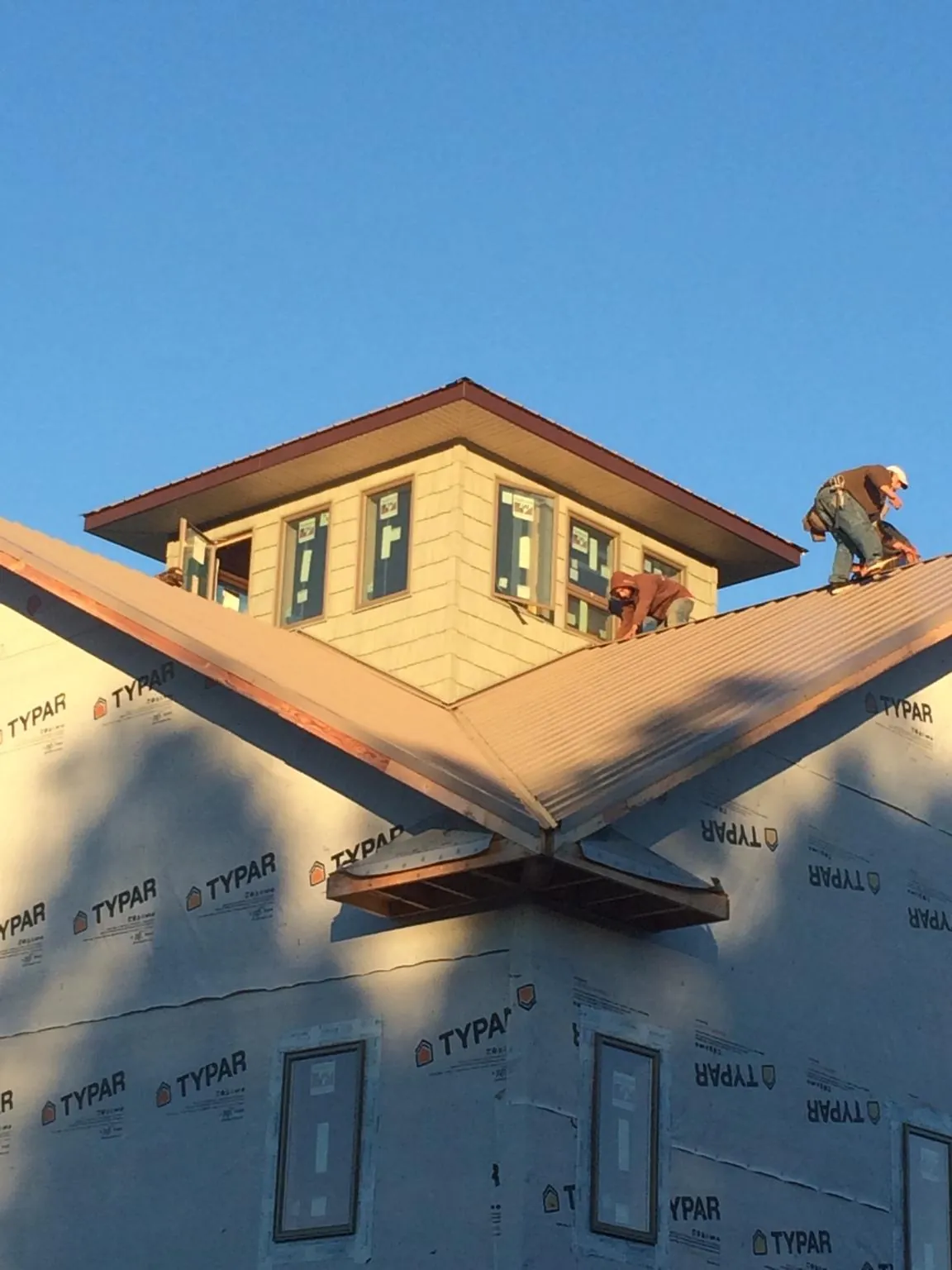Roofers working around a rooftop cupola on a new metal roof at sunset — Roof Waterproofing in Twain Harte by Roofing Brothers